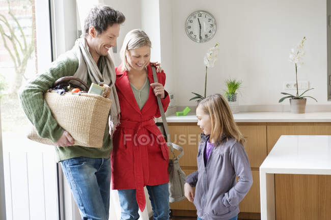 Familia feliz entrando en casa y sonriendo - foto de stock