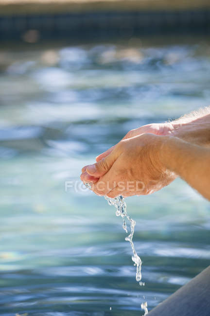 Primo piano di mani maschili ricoperte con acqua della piscina — Foto stock