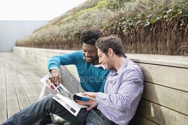 Male friends choosing color swatches on boardwalk in nature — Stock Photo
