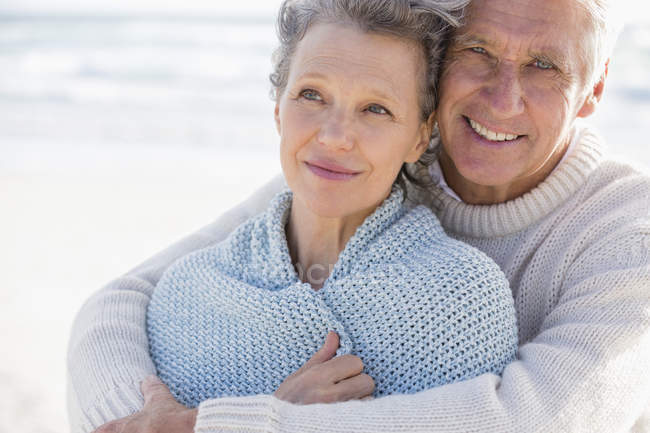 Щасливий чоловік обіймає дружину ззаду на пляжі — стокове фото