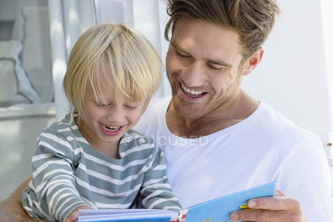 Heureux père et fils lisant un livre — Photo de stock