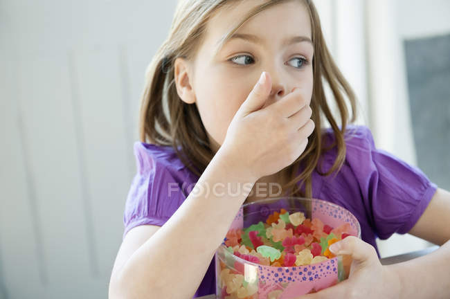 Petite fille tenant boîte pleine de bonbons à la gomme — Photo de stock