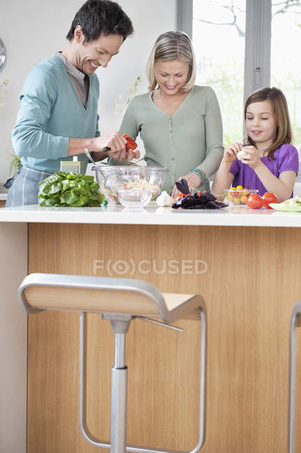 Счастливая семья готовит еду на кухне — стоковое фото
