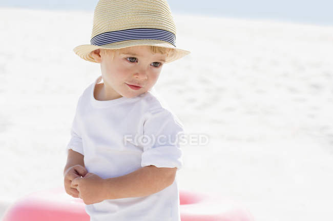 Nahaufnahme eines niedlichen Jungen mit Strohhut, der am Strand steht — Stockfoto