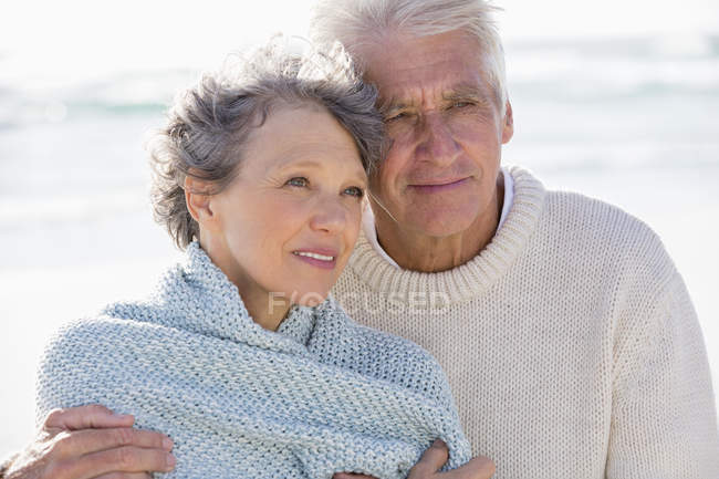 Close-up of thoughtful senior couple embracing on beach — Stock Photo