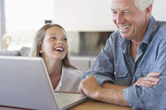 Mann zeigt Enkelin Laptop und lacht — Stockfoto