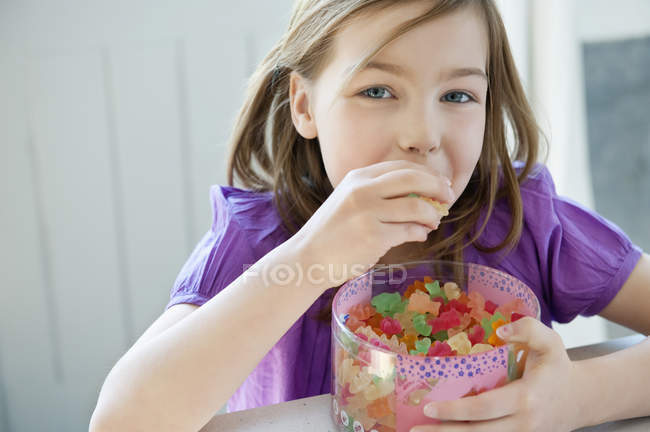 Усміхнена маленька дівчинка тримає коробку повну цукерок з гумок — стокове фото