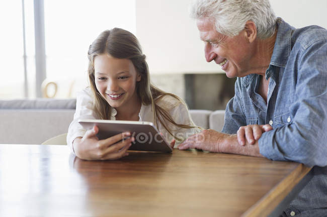 Mädchen mit digitalem Tablet und Opa am Schreibtisch — Stockfoto