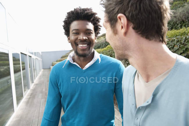 Smiling friends discussing on boardwalk in nature — Stock Photo