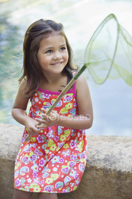 Kleines Mädchen sitzt mit Netz in der Hand am Swimmingpool — Stockfoto