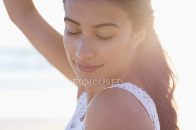 Nahaufnahme einer nachdenklichen jungen Frau mit geschlossenen Augen, die im Sonnenlicht posiert — Stockfoto