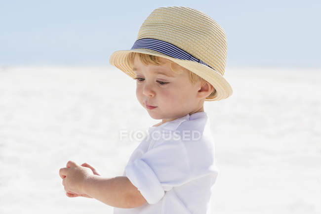 Close-up of cute baby boy in straw hat playing on beach — Stock Photo