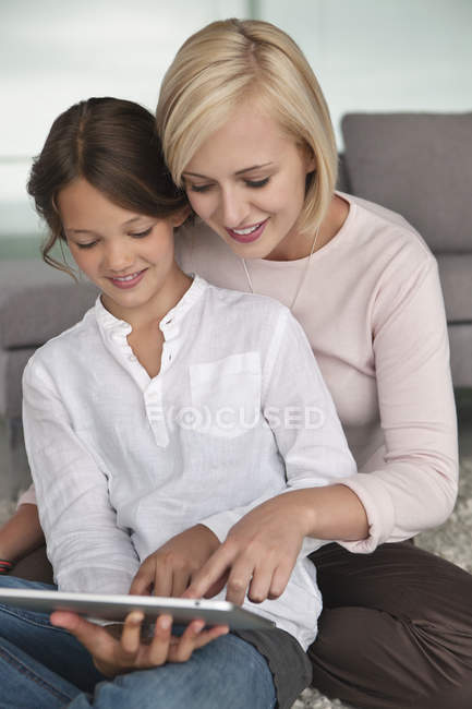 Frau hilft Tochter beim Umgang mit digitalem Tablet — Stockfoto