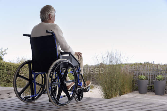 Homem sênior em cadeira de rodas relaxante ao ar livre — Fotografia de Stock