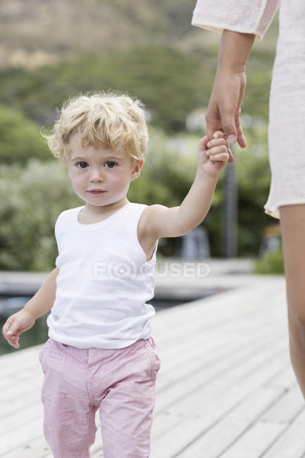 Портрет маленького мальчика, гуляющего с матерью у бассейна — стоковое фото