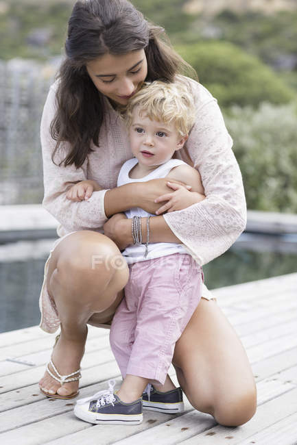 Щаслива мати грає з сином біля басейну — стокове фото