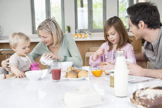 Familia feliz divirtiéndose en la mesa del desayuno - foto de stock
