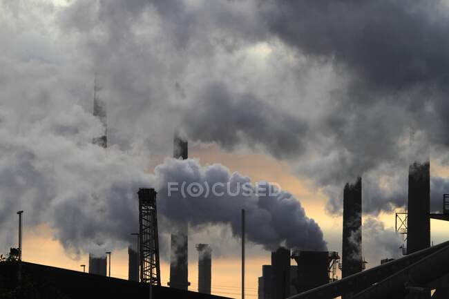 Нидерланды, заводские дымовые трубы на закате — стоковое фото