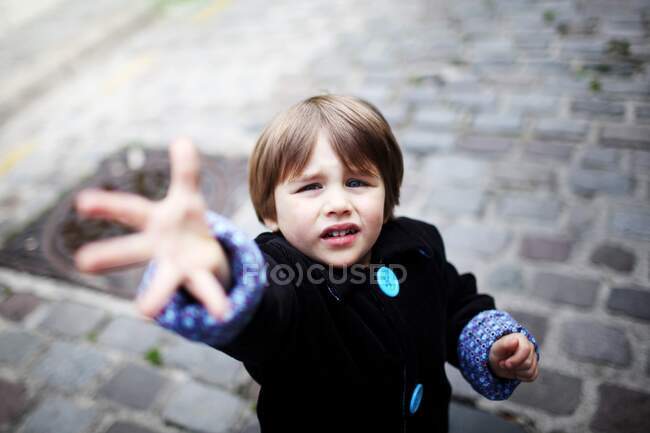 Маленький хлопчик з простягнутою рукою на вулиці — стокове фото