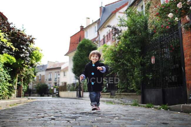 Маленький хлопчик біжить у забитій вузькій вулиці — стокове фото