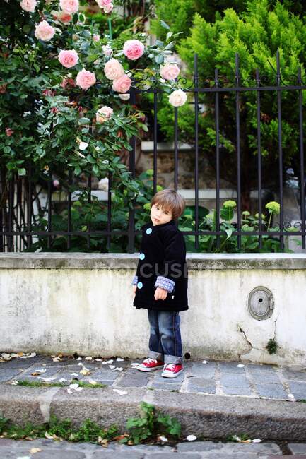 Маленький мальчик дуется на мощеной узкой улице — стоковое фото