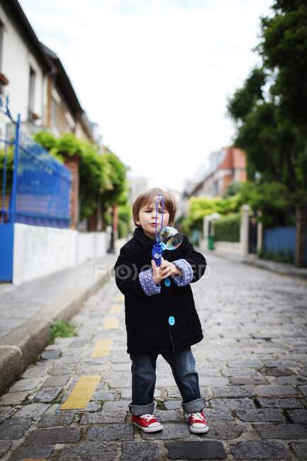 Little boy blowing bubbles in the street — Stock Photo