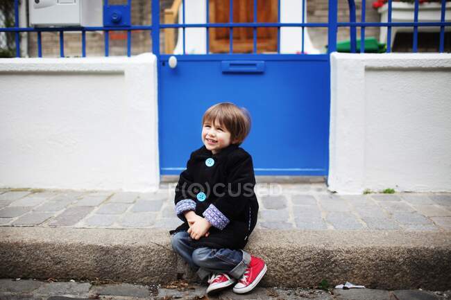 Niño sentado en la acera - foto de stock