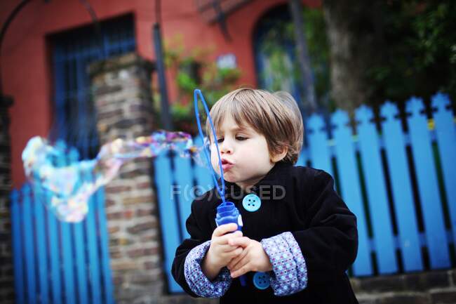Little boy blowing bubbles in the street — Stock Photo