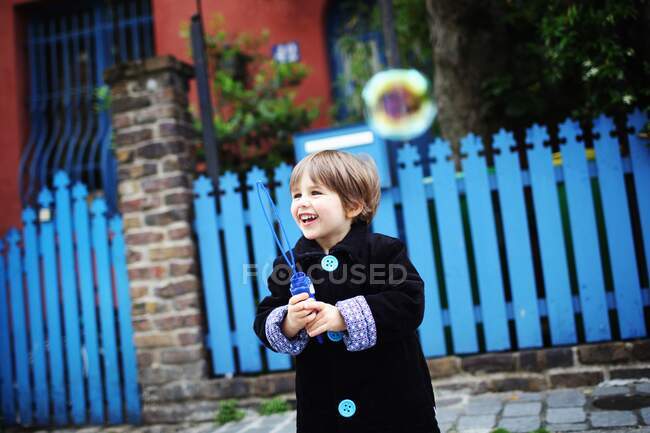 Маленький хлопчик дме бульбашки на вулиці — стокове фото