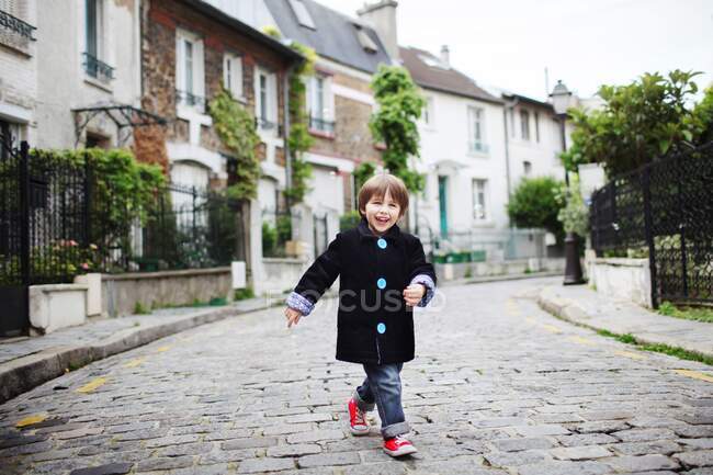 Petit garçon marchant dans une rue étroite pavée — Photo de stock