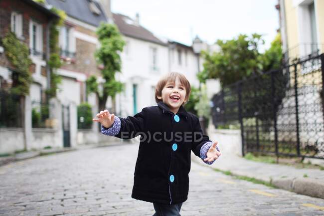 Menino correndo em uma rua estreita de paralelepípedos — Fotografia de Stock