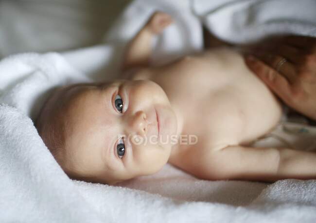 Portrait of a 4 months old baby, lying on a white towel — Stock Photo