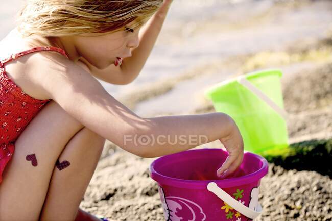 Menina pequena brincando com um balde na praia — Fotografia de Stock