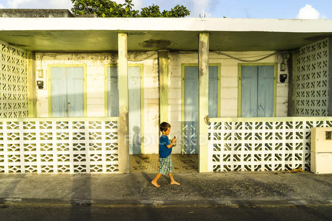 Un niño frente a una casa tradicional, Saint-Louis, Marie-Galante, Guadalupe, Francia - foto de stock
