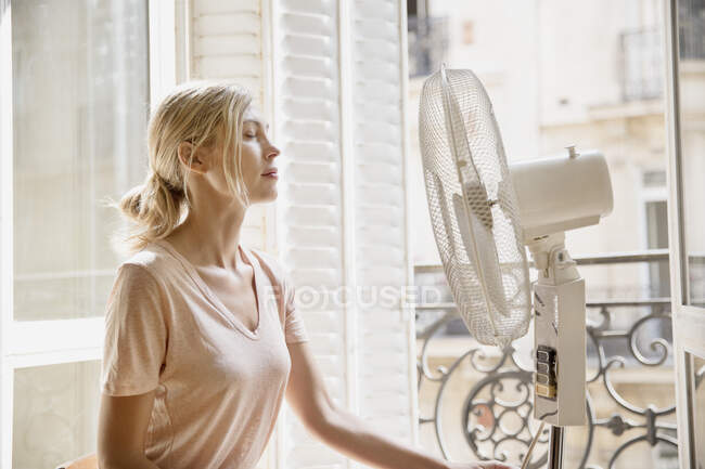 Jeune femme de profil devant un ventilateur. — Photo de stock