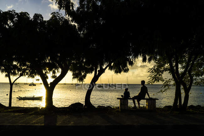 A father and his son sitted in front of the sunset, Saint-Louis, Marie-Galante, Guadeloupe, France — Stock Photo
