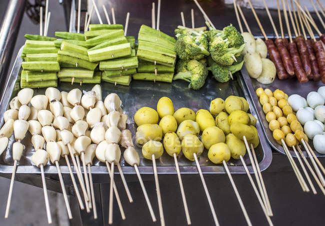 Brochetas de verduras en el mercado callejero en el distrito chino - foto de stock