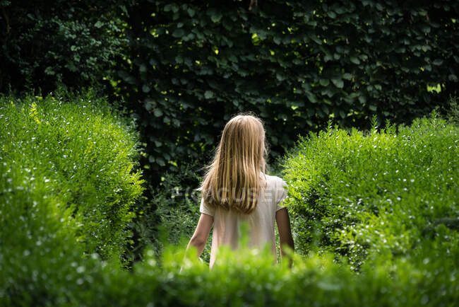 Rücken eines jungen Mädchens mit blonden Haaren in einem Bauerngarten — Stockfoto