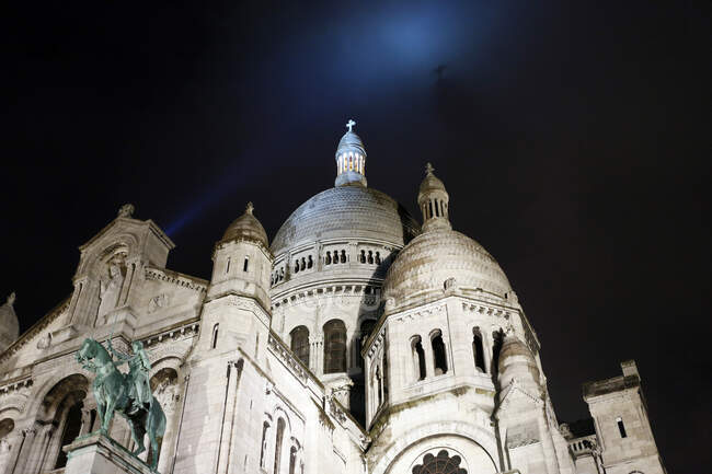 París, distrito 18, Montmartre, Basílica del Sagrado Corazón por la noche. Cruz de Cristo proyectada sobre las nubes. - foto de stock