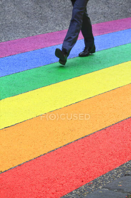 Homme marchant sur des rayures de couleur, comme un drapeau arc-en-ciel — Photo de stock