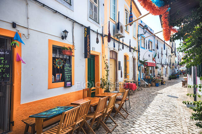 Restaurante terrazas en una calle pavimentada del pueblo Ferragudo, región del Algarve, Portugal - foto de stock