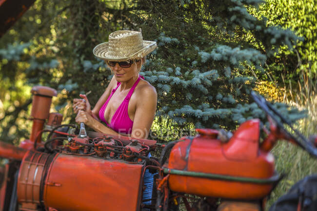 Sexy women repairing the tractor engine in the countryside — Stock Photo