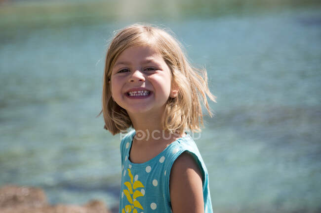 Портрет дуже гарненької дівчинки, яка посміхається, дивлячись на море . — стокове фото