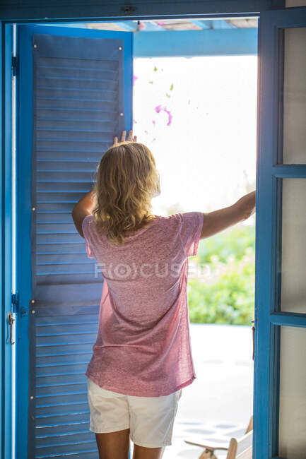 Junge blonde Frau öffnet Rollläden, um zu lüften. — Stockfoto