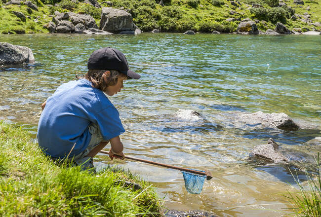 France, Pyrenees National Park, Val d'Azun, 6-year-old boy fishing by the Suyen lake on the gave d'Arrens (name referring to torrential rivers, in the west side of the Pyrenees). — Stock Photo