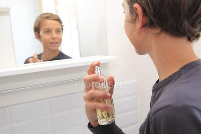 Francia, adolescente en su cuarto de baño usando parfum. - foto de stock