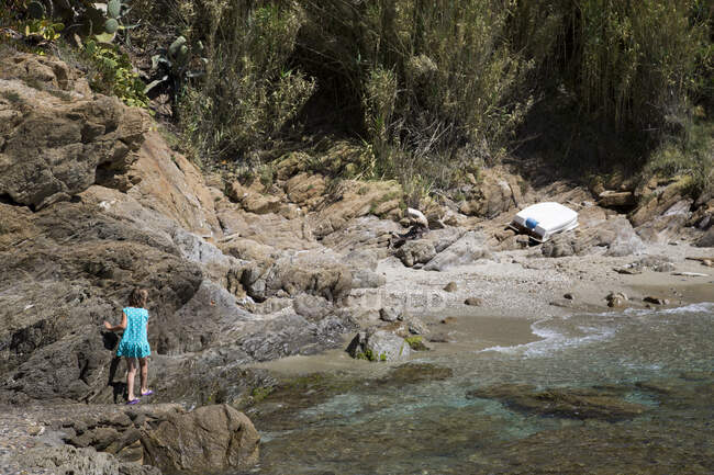 View of a rocky coastal landscape with a little girl swaying on the way. — Stock Photo