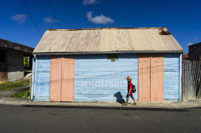 Un bambino davanti a una casa rosa e blu, Saint-Louis, Marie-Galante, Guadalupa, Francia — Foto stock