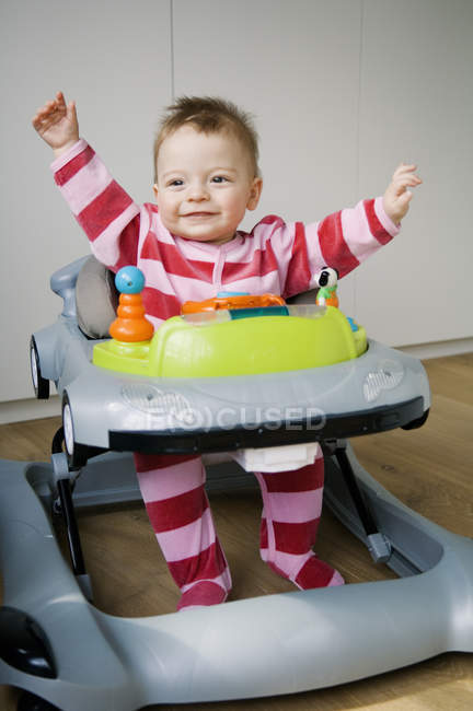 Menino alegre sentado em um baby-walker — Fotografia de Stock