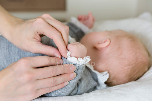 Mãos de uma mãe que veste seu bebê em uma mesa de mudança. — Fotografia de Stock